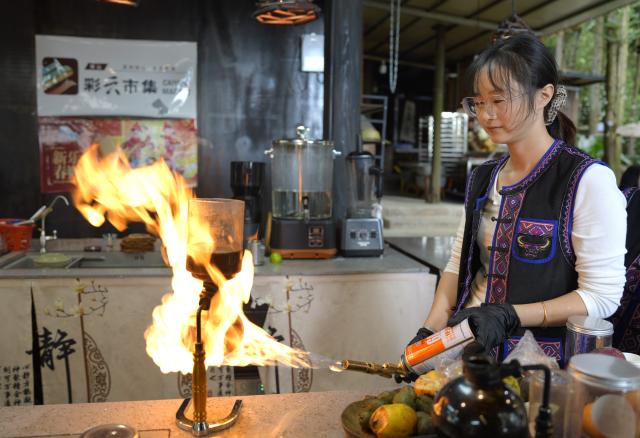 (261020) -- TENGCHONG, Oct. 20, 2026 (Xinhua) -- A staff member makes coffee at a cafe in Simola Wa Village in Qingshui Town of Tengchong City, southwest China's Yunnan Province, Oct. 19, 2026. The Simola Wa Village has a history of over 500 years and is home to people of multiple ethnic groups including the Wa, Han, Bai and Dai. Simola means "a place of happiness" in the Wa language. In recent years, the village has relied on its ethnic cultural resources to create a distinctive cultural tourism industry, attracting a continuous stream of tourists. (Xinhua/Wang Chutian)