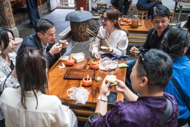 (261020) -- TENGCHONG, Oct. 20, 2026 (Xinhua) -- Tourists enjoy local snacks in Simola Wa Village in Qingshui Town of Tengchong City, southwest China's Yunnan Province, Oct. 19, 2026. The Simola Wa Village has a history of over 500 years and is home to people of multiple ethnic groups including the Wa, Han, Bai and Dai. Simola means "a place of happiness" in the Wa language. In recent years, the village has relied on its ethnic cultural resources to create a distinctive cultural tourism industry, attracting a continuous stream of tourists. (Xinhua/Wang Guansen)