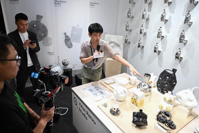 (261020) -- BEIJING, Oct. 20, 2026 (Xinhua) -- An exhibitor introduces artworks at the 2026 Beijing China Art International Fair in Beijing, capital of China, Oct. 20, 2026. With a theme of "Cultural Heritage Bridges Life to a Vibrant World", the fair kicked off here on Tuesday. (Xinhua/Chen Zhonghao)