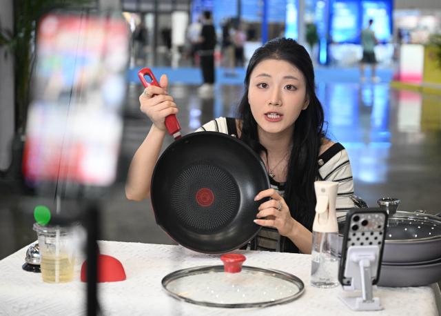 (261020) -- HAIKOU, Oct. 20, 2026 (Xinhua) -- A staff member introduces a pan product via livestreaming at the China Brands Export Expo in Haikou, south China's Hainan Province, Oct. 20, 2026. The three-day expo kicked off here on Tuesday. (Xinhua/Pu Xiaoxu)
