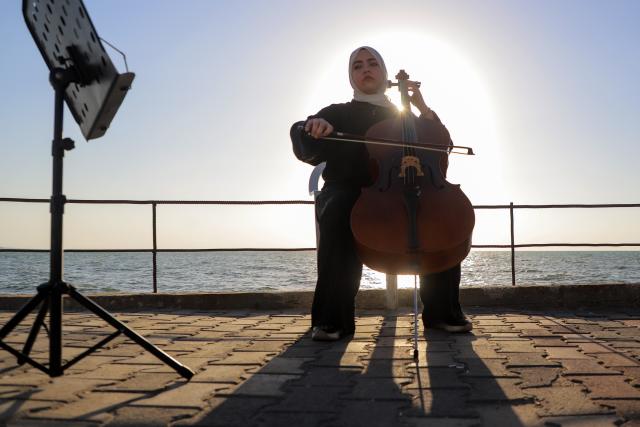 (261021) -- GAZA, Oct. 21, 2026 (Xinhua) -- Palestinian artist Haifa Bassam Abu Shamla plays the cello at a cafe near the seaside in Gaza City, on Oct. 4, 2026.
  TO GO WITH "Letter from Mideast: In Gaza, my cello sings of more than survival" (Photo by Rizek Abdeljawad/Xinhua)