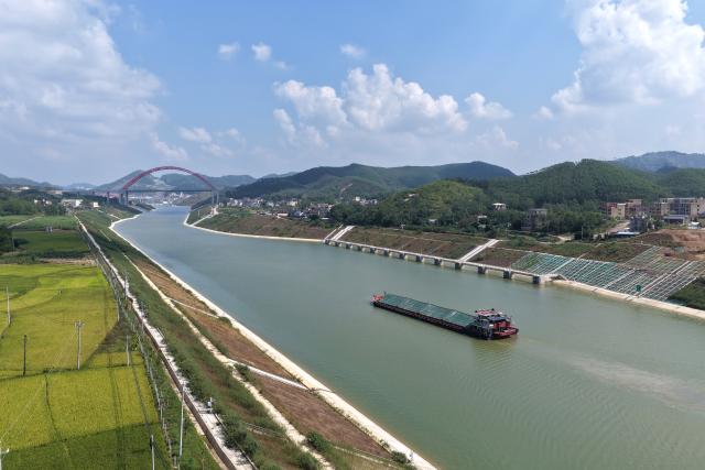 (261021) -- QINZHOU, Oct. 21, 2026 (Xinhua) -- An aerial drone photo taken on Oct. 21, 2026 shows a cargo vessel near the Jiuzhou bridge over the Pinglu Canal in south China's Guangxi Zhuang Autonomous Region. Cargo throughput of the Pinglu Canal has surpassed 1 million tonnes since its opening to navigation on Sept. 16.
  The 134.2-kilometer canal runs from Nanning, capital of south China's Guangxi Zhuang Autonomous Region, to the Beibu Gulf, the closest maritime outlet for much of southwest China.
  The canal stretches along the New International Land-Sea Trade Corridor, a strategic trade route connecting China's inland regions with ASEAN and other global markets. It is the first river-to-sea canal project planned and coordinated at the national level since the founding of the People's Republic of China in 1949. (Xinhua/Zhou Hua)