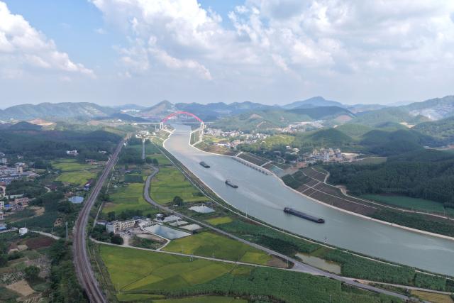 (261021) -- QINZHOU, Oct. 21, 2026 (Xinhua) -- An aerial drone photo taken on Oct. 21, 2026 shows cargo vessels near the Jiuzhou bridge over the Pinglu Canal in south China's Guangxi Zhuang Autonomous Region. Cargo throughput of the Pinglu Canal has surpassed 1 million tonnes since its opening to navigation on Sept. 16.
  The 134.2-kilometer canal runs from Nanning, capital of south China's Guangxi Zhuang Autonomous Region, to the Beibu Gulf, the closest maritime outlet for much of southwest China.
  The canal stretches along the New International Land-Sea Trade Corridor, a strategic trade route connecting China's inland regions with ASEAN and other global markets. It is the first river-to-sea canal project planned and coordinated at the national level since the founding of the People's Republic of China in 1949. (Xinhua/Zhou Hua)