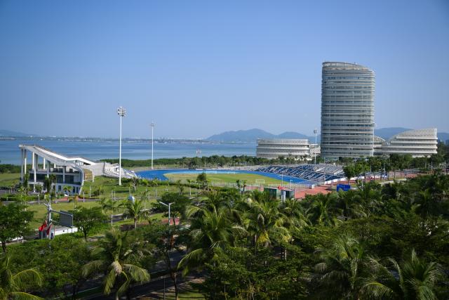 (261023) -- LINGSHUI, Oct. 23, 2026 (Xinhua) -- This photo taken on Oct. 22, 2026 shows a stadium and buildings at Lingshui Li'an International Education Innovation Pilot Zone in Lingshui Li Autonomous County, south China's Hainan Province.
  As China's highland of educational opening up and innovation, Lingshui Li'an International Education Innovation Pilot Zone started construction in 2020. So far, over 30 renowned colleges and universities from home and abroad have settled in the pilot zone.
  The pilot zone is promoting as well as encouraging overseas high-level universities to run independent schools in the zone. It adopts an innovative model that all the universities have their own buildings, but share public facilities including the library, sports venues and public teaching buildings. (Xinhua/Xin Yuewei)