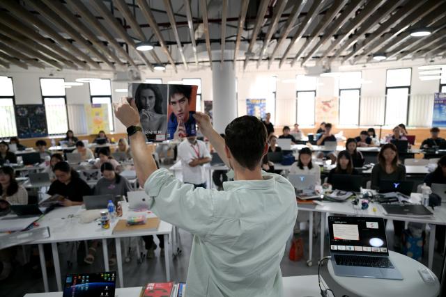 (261023) -- LINGSHUI, Oct. 23, 2026 (Xinhua) -- A foreign teacher gives a graphic design lesson at the Hainan International College of Minzu University of China at Lingshui Li'an International Education Innovation Pilot Zone in Lingshui Li Autonomous County, south China's Hainan Province, Oct. 22, 2026.
  As China's highland of educational opening up and innovation, Lingshui Li'an International Education Innovation Pilot Zone started construction in 2020. So far, over 30 renowned colleges and universities from home and abroad have settled in the pilot zone.
  The pilot zone is promoting as well as encouraging overseas high-level universities to run independent schools in the zone. It adopts an innovative model that all the universities have their own buildings, but share public facilities including the library, sports venues and public teaching buildings. (Xinhua/Xin Yuewei)