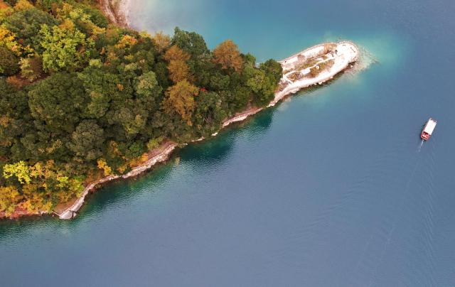 (261023) -- WENXIAN, Oct. 23, 2026 (Xinhua) -- An aerial drone photo taken on Oct. 22, 2026 shows a tourist boat sailing at Tianchi lake national forest park in Wenxian County, northwest China's Gansu Province. In late autumn, Tianchi lake national forest park is adorned with richly colored foliage. (Xinhua/Chen Bin)