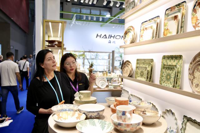 (261023) -- GUANGZHOU, Oct. 23, 2026 (Xinhua) -- A foreign buyer learns about ceramic products during the second phase of the 140th Canton Fair in Guangzhou, south China's Guangdong Province, Oct. 23, 2026. The second phase of the 140th China Import and Export Fair, also known as the Canton Fair, kicked off here on Friday. Themed "Quality Home Life," the second phase covered 515,000 square meters, with over 10,000 participating enterprises. (Xinhua/Lu Hanxin)