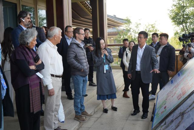(261023) -- XIONG'AN, Oct. 23, 2026 (Xinhua) -- Participants of the 2026 Global Governance Forum (Xiong'an) listen to the introduction of the construction of Xiong'an New area while visiting the start-up zone of Xiong'an in north China's Hebei Province, Oct. 23, 2026. The 2026 Global Governance Forum (Xiong'an) kicked off here on Friday and will last till Sunday. Participants from various countries and regions visited a smart-city science and innovation center and the construction site of the start-up zone of Xiong'an New Area ahead of the forum. (Xinhua/Su Kaiyang)