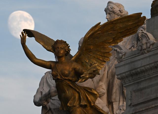 (261023) -- ROME, Oct. 23, 2026 (Xinhua) -- The moon is seen behind statues in Piazza Venezia in Rome, Italy, Oct. 23, 2026. (Photo by Alberto Lingria/Xinhua)