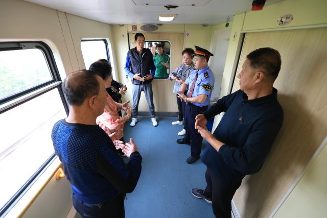 (261024) -- HARBIN, Oct. 24, 2026 (Xinhua) -- The chief conductor of the train Z114/111 leads passengers in practicing Baduanjin, a traditional Chinese exercise, aboard the train on Oct. 22, 2026.
  The train Z114/111, running between Harbin in northeast China's Heilongjiang Province and Haikou in south China's Hainan Province, has witnessed a surge of passengers before winter arrives in Heilongjiang.
  The train service, which takes about 48 hours to finish the 4,300-km-long journey, is popular among elderly travelers from northeast China heading south to escape the bitter winter cold. (Photo by Xu Shuai/Xinhua)