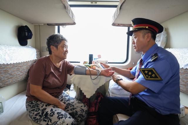 (261024) -- HARBIN, Oct. 24, 2026 (Xinhua) -- The chief conductor of the train Z114/111 measures blood pressure for a passenger aboard the train on Oct. 22, 2026.
  The train Z114/111, running between Harbin in northeast China's Heilongjiang Province and Haikou in south China's Hainan Province, has witnessed a surge of passengers before winter arrives in Heilongjiang.
  The train service, which takes about 48 hours to finish the 4,300-km-long journey, is popular among elderly travelers from northeast China heading south to escape the bitter winter cold. (Photo by Xu Shuai/Xinhua)