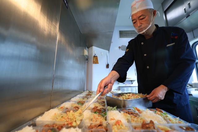(261024) -- HARBIN, Oct. 24, 2026 (Xinhua) -- A staff member prepares meals for passengers aboard the train Z114/111 on Oct. 22, 2026.
  The train Z114/111, running between Harbin in northeast China's Heilongjiang Province and Haikou in south China's Hainan Province, has witnessed a surge of passengers before winter arrives in Heilongjiang.
  The train service, which takes about 48 hours to finish the 4,300-km-long journey, is popular among elderly travelers from northeast China heading south to escape the bitter winter cold. (Photo by Xu Shuai/Xinhua)