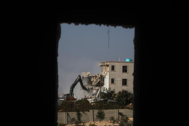 (261024) -- HEBRON, Oct. 24, 2026 (Xinhua) -- A bulldozer demolishes a residential building near the northern entrance of the West Bank city of Hebron, on Oct. 23, 2026. Israel is preparing a major military operation in the West Bank, Israeli Prime Minister Benjamin Netanyahu said Friday, as local sources said Israeli forces demolished a residential building in Hebron and closed the city's main entrances following a shooting attack that killed two Israeli soldiers and two Palestinian attackers. (Photo by Mamoun Wazwaz/Xinhua)