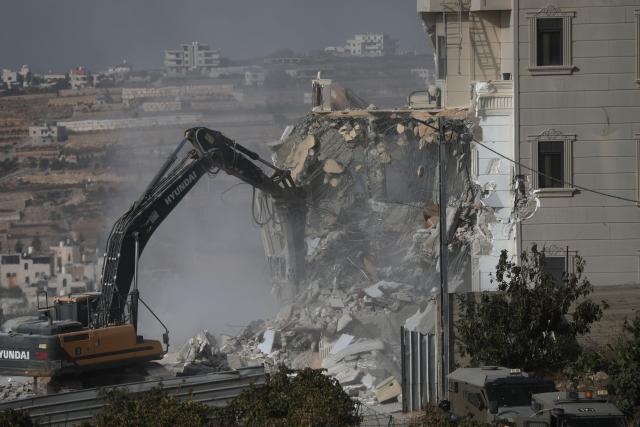 (261024) -- HEBRON, Oct. 24, 2026 (Xinhua) -- A bulldozer demolishes a residential building near the northern entrance of the West Bank city of Hebron, on Oct. 23, 2026. Israel is preparing a major military operation in the West Bank, Israeli Prime Minister Benjamin Netanyahu said Friday, as local sources said Israeli forces demolished a residential building in Hebron and closed the city's main entrances following a shooting attack that killed two Israeli soldiers and two Palestinian attackers. (Photo by Mamoun Wazwaz/Xinhua)