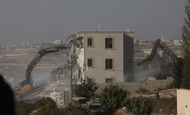(261024) -- HEBRON, Oct. 24, 2026 (Xinhua) -- Bulldozers demolish a residential building near the northern entrance of the West Bank city of Hebron, on Oct. 23, 2026. Israel is preparing a major military operation in the West Bank, Israeli Prime Minister Benjamin Netanyahu said Friday, as local sources said Israeli forces demolished a residential building in Hebron and closed the city's main entrances following a shooting attack that killed two Israeli soldiers and two Palestinian attackers. (Photo by Mamoun Wazwaz/Xinhua)