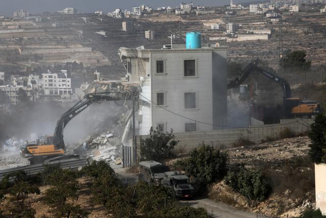 (261024) -- HEBRON, Oct. 24, 2026 (Xinhua) -- Bulldozers demolish a residential building near the northern entrance of the West Bank city of Hebron, on Oct. 23, 2026. Israel is preparing a major military operation in the West Bank, Israeli Prime Minister Benjamin Netanyahu said Friday, as local sources said Israeli forces demolished a residential building in Hebron and closed the city's main entrances following a shooting attack that killed two Israeli soldiers and two Palestinian attackers. (Photo by Mamoun Wazwaz/Xinhua)