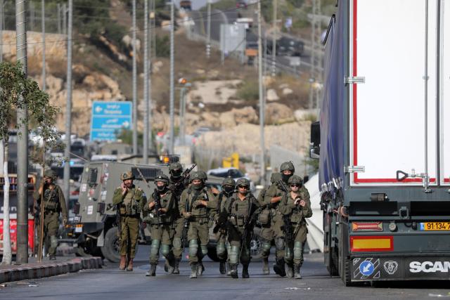 (261024) -- HEBRON, Oct. 24, 2026 (Xinhua) -- Israeli soldiers stand guard at the northern checkpoint of the West Bank city of Hebron, Oct. 23, 2026. Israeli forces launched a military operation in the West Bank city of Hebron on Friday night, hours after Israeli leaders vowed to displace residents and carry out demolitions following a shooting attack near the city that killed two Israeli soldiers. (Photo by Mamoun Wazwaz/Xinhua)