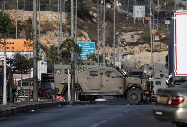 (261024) -- HEBRON, Oct. 24, 2026 (Xinhua) -- An Israeli vehicle blocks the northern checkpoint of the West Bank city of Hebron, Oct. 23, 2026. Israeli forces launched a military operation in the West Bank city of Hebron on Friday night, hours after Israeli leaders vowed to displace residents and carry out demolitions following a shooting attack near the city that killed two Israeli soldiers. (Photo by Mamoun Wazwaz/Xinhua)