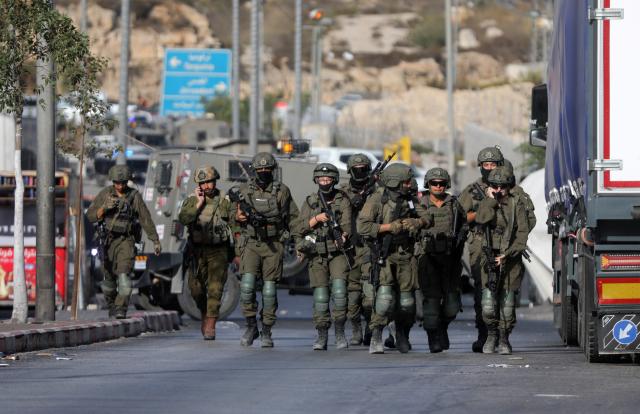 (261024) -- HEBRON, Oct. 24, 2026 (Xinhua) -- Israeli soldiers stand guard at the northern checkpoint of the West Bank city of Hebron, Oct. 23, 2026. Israeli forces launched a military operation in the West Bank city of Hebron on Friday night, hours after Israeli leaders vowed to displace residents and carry out demolitions following a shooting attack near the city that killed two Israeli soldiers. (Photo by Mamoun Wazwaz/Xinhua)
