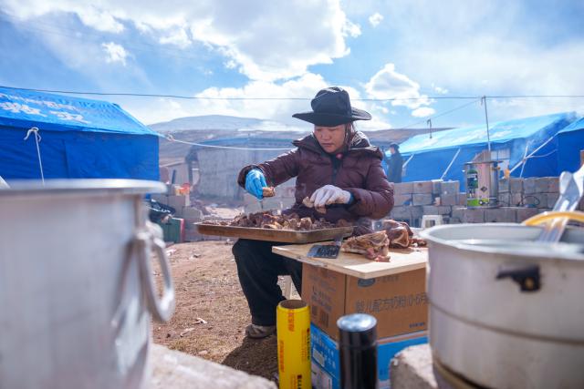 (261024) -- NAGQU, Oct. 24, 2026 (Xinhua) -- A staff member of the local government prepares food at a quake-hit village in Maru Township of Baqen County, Nagqu City, southwest China's Xizang Autonomous Region, Oct. 24, 2026. As of 11 a.m. Saturday, 52,450 items or sets of disaster relief supplies had been sent to the quake zone, while more than 2,500 rescue personnel were engaged in relief operations.
   Authorities have established 35 temporary resettlement sites in the disaster zone. Medical treatment and public health and epidemic prevention efforts are proceeding in an orderly manner, according to the local emergency command headquarters. (Xinhua/Tenzin Nyida)