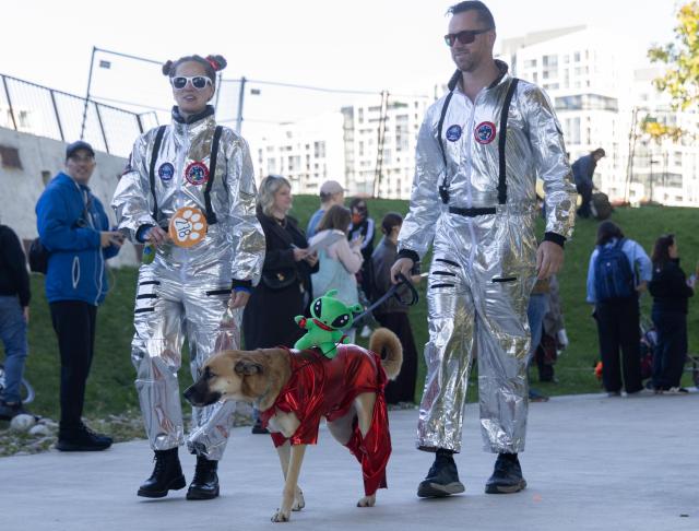 (261025) -- TORONTO, Oct. 25, 2026 (Xinhua) -- A dog and its owners take part in "Howl'oween at the Bentway," a dog-and-owner costume contest, in Toronto, Canada, on Oct. 24, 2026. The annual event was held here on Saturday, bringing Halloween fun for dogs and their owners. (Photo by Zou Zheng/Xinhua)