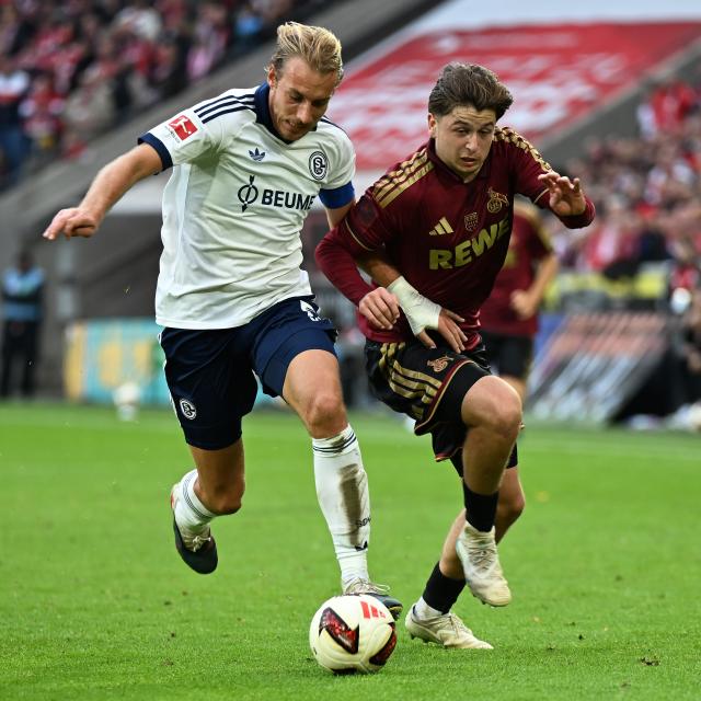 (261025) -- COLOGNE, Oct. 25, 2026 (Xinhua) -- Mikey Moore (R) of FC Cologne vies with Timo Becker of FC Schalke 04 during the German first division Bundesliga football match between FC Cologne and FC Schalke 04 in Cologne, Germany, Oct. 24, 2026. (Photo by Ulrich Hufnagel/Xinhua)