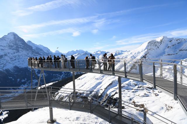 (261025) -- GENEVA, Oct. 25, 2026 (Xinhua) -- This file photo shows visitors viewing the snow-covered mountain scenery from the First Cliff Walk at Grindelwald-First mountain in the canton of Bern, Switzerland, Dec. 18, 2025. TO GO WITH "Feature: Taste of China's Wuyi Mountain at Switzerland's Grindelwald-First" (Xinhua/Lian Yi)