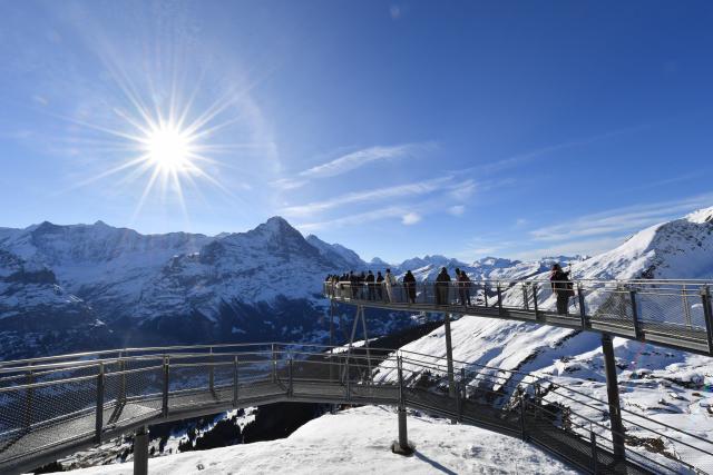 (261025) -- GENEVA, Oct. 25, 2026 (Xinhua) -- This file photo shows visitors viewing the snow-covered mountain scenery from the First Cliff Walk at Grindelwald-First mountain in the canton of Bern, Switzerland, Dec. 18, 2025. TO GO WITH "Feature: Taste of China's Wuyi Mountain at Switzerland's Grindelwald-First" (Xinhua/Lian Yi)