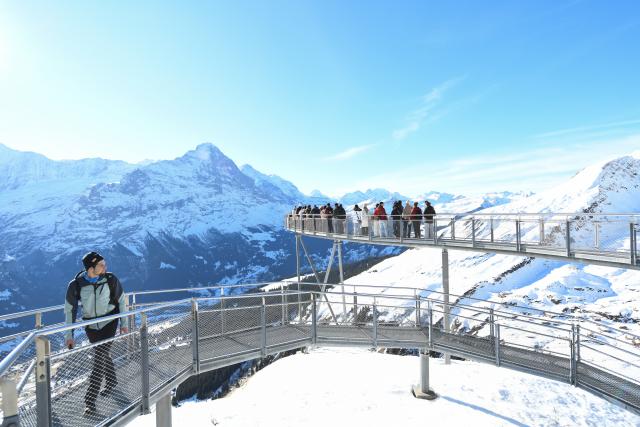 (261025) -- GENEVA, Oct. 25, 2026 (Xinhua) -- This file photo shows visitors viewing the snow-covered mountain scenery from the First Cliff Walk at Grindelwald-First mountain in the canton of Bern, Switzerland, Dec. 18, 2025. TO GO WITH "Feature: Taste of China's Wuyi Mountain at Switzerland's Grindelwald-First" (Xinhua/Lian Yi)