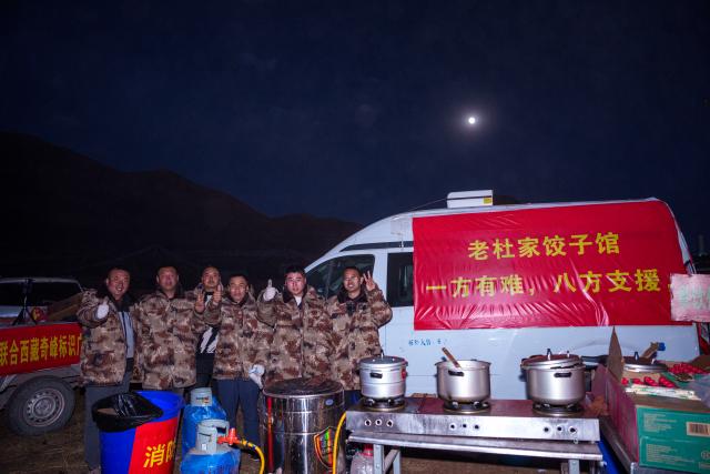 (261025) -- BAQEN, Oct. 25, 2026 (Xinhua) -- Du Guoping (1st R) poses for a photo with his staff members at a temporary shelter in Maru Township of Baqen County, Nagqu City, southwest China's Xizang Autonomous Region, Oct. 24, 2026. After a 7.0-magnitude earthquake struck Baqen County in Nagqu, southwest China's Xizang Autonomous Region, on Thursday, Du Guoping, owner of a dumpling restaurant in Xigaze, postponed the opening of his two new restaurants and headed to the disaster zone with his staff.
  "It took only about 10 minutes to make the decision that we would go to Baqen and cook dumplings for earthquake-affected residents," Du said.
  The team loaded more than 1,500 kilograms of dumplings onto vehicles and set off from Xigaze at midnight on the night of the earthquake. 
  Upon arrival, Du and his staff set up cooking equipment and prepared dumplings for rescue workers and affected residents.
"Make sure everyone gets enough dumplings, and give children a couple more," Du kept telling his staff.
  Du and his staff did not eat any of the dumplings themselves. After a full day of cooking, they had some instant noodles -- their only meal of the day. At night, the six team members of Du squeezed into two vehicles to rest.
  "We will cook all the dumplings we brought," Du said. "We feel honored to be able to contribute in our own way." (Xinhua/Tenzin Nyida)