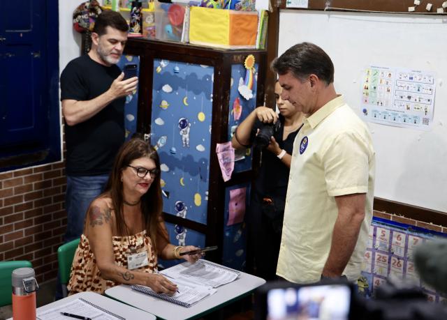 (261025) -- RIO DE JANEIRO, Oct. 25, 2026 (Xinhua) -- Flavio Bolsonaro (1st R), presidential candidate of Brazil's Liberal Party, undergoes an identity check before casting a ballot at a polling station in Rio de Janeiro, Brazil, Oct. 25, 2026. Voting in the second round of Brazil's 2026 presidential election officially began at 8 a.m. local time (1100 GMT) on Sunday, with polling stations across the nation set to close at 5 p.m. local time (2000 GMT).
   Incumbent President Luiz Inacio Lula da Silva of the ruling Workers' Party faces Flavio Bolsonaro, the Liberal Party candidate and son of former President Jair Bolsonaro, in the runoff after the two topped the first-round vote. (Xinhua/Jin Haoyuan)
