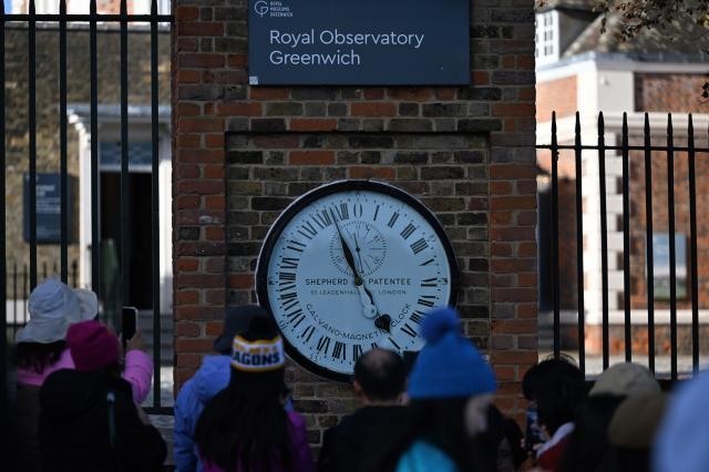 (261025) -- LONDON, Oct. 25, 2026 (Xinhua) -- Visitors watch the Shepherd Gate Clock at the entrance to the Royal Observatory in Greenwich, London, Britain, on Oct. 25, 2026. The clock was the world's first to display Greenwich Mean Time (GMT) directly to the public and features a 24-hour dial. Britain ended British Summer Time (BST) at 2am on Sunday, October 25, 2026, setting clocks back one hour to Greenwich Mean Time (GMT). (Xinhua/Li Mangmang)