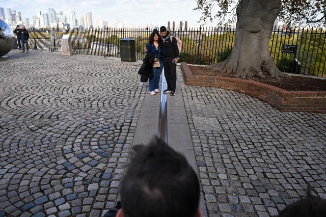 (261026) -- LONDON, Oct. 26, 2026 (Xinhua) -- A couple pose for photos at the historic Prime Meridian line at the Royal Observatory in Greenwich, London, Britain, on Oct. 25, 2026. The Royal Observatory in Greenwich was founded in 1675 to improve navigation at sea through astronomical observations and help ships determine their longitude. As the home of Greenwich Mean Time, it holds an important place in the history of astronomy, precision timekeeping and navigation. In 1884, the meridian passing through the observatory was adopted as the international Prime Meridian, establishing a common reference for measuring longitude worldwide. This historic line is still marked at the observatory today. (Xinhua/Li Mangmang)