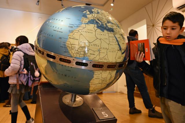 (261026) -- LONDON, Oct. 26, 2026 (Xinhua) -- A young visitor views a large globe displaying the time around the world at the Royal Observatory in Greenwich, London, Britain, on Oct. 25, 2026. The Royal Observatory in Greenwich was founded in 1675 to improve navigation at sea through astronomical observations and help ships determine their longitude. As the home of Greenwich Mean Time, it holds an important place in the history of astronomy, precision timekeeping and navigation. In 1884, the meridian passing through the observatory was adopted as the international Prime Meridian, establishing a common reference for measuring longitude worldwide. This historic line is still marked at the observatory today. (Xinhua/Li Mangmang)