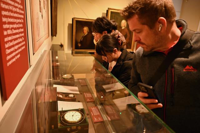 (261026) -- LONDON, Oct. 26, 2026 (Xinhua) -- Visitors look at marine chronometers on display at the Royal Observatory in Greenwich, London, Britain, on Oct. 25, 2026. The Royal Observatory in Greenwich was founded in 1675 to improve navigation at sea through astronomical observations and help ships determine their longitude. As the home of Greenwich Mean Time, it holds an important place in the history of astronomy, precision timekeeping and navigation. In 1884, the meridian passing through the observatory was adopted as the international Prime Meridian, establishing a common reference for measuring longitude worldwide. This historic line is still marked at the observatory today. (Xinhua/Li Mangmang)