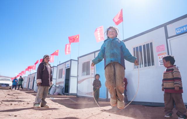 (261026) -- BAQEN, Oct. 26, 2026 (Xinhua) -- Children play at a resettlement site of a quake-hit village in Maru Township of Baqen County, Nagqu City, southwest China's Xizang Autonomous Region, Oct. 26, 2026.
  The first 60 prefabricated housing units in the earthquake zone were completed at 2:10 a.m. on Oct. 25, and electricity was connected to the units by 8 p.m. on the same day. (Xinhua/Tenzin Nyida)