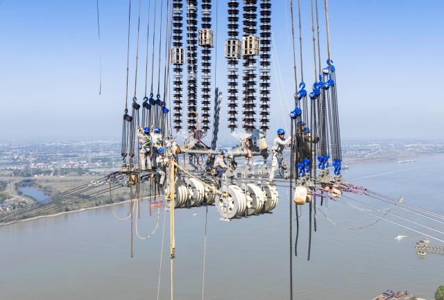 (261026) -- WUHU, Oct. 26, 2026 (Xinhua) -- A drone photo shows power technicians working at a construction site of the ±800kV ultra-high-voltage direct current (UHVDC) transmission project along the Yangtze River in Wuhu, east China's Anhui Province, Oct. 26, 2026.
  The ±800kV UHVDC transmission project completed the large-span stringing construction across the Yangtze River on Monday in the city of Wuhu, Anhui Province.
  The project has a total length of 2,370 kilometers from northwest China's Gansu Province to east China's Zhejiang Province. Once operational, it will be able to transmit more than 36 billion kWh of electricity to Zhejiang Province annually. (Photo by Zheng Xianlie/Xinhua)