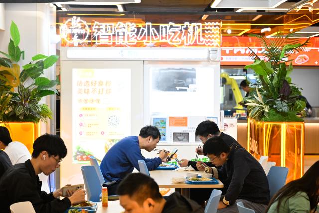 (261026) -- NANJING, Oct. 26, 2026 (Xinhua) -- People dine at the AI Mirror World Restaurant in Nanjing, east China's Jiangsu Province, Oct. 26, 2026. With a human-machine collaborative operation model, the restaurant makes some of its meals and drinks through standardized production powered by AI kitchen equipped with smart noodle and beverage making machines. (Xinhua/Ji Chunpeng)