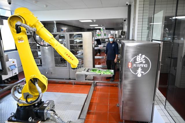 (261026) -- NANJING, Oct. 26, 2026 (Xinhua) -- A robotic arm transports ingredients in the kitchen of the AI Mirror World Restaurant in Nanjing, east China's Jiangsu Province, Oct. 26, 2026. With a human-machine collaborative operation model, the restaurant makes some of its meals and drinks through standardized production powered by AI kitchen equipped with smart noodle and beverage making machines. (Xinhua/Ji Chunpeng)