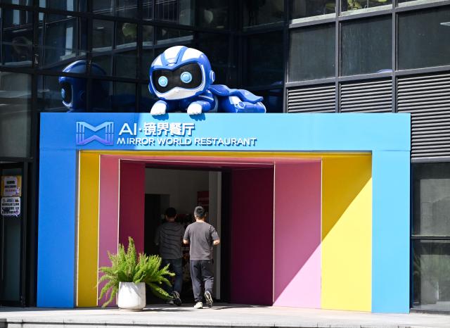 (261026) -- NANJING, Oct. 26, 2026 (Xinhua) -- People walk into the AI Mirror World Restaurant in Nanjing, east China's Jiangsu Province, Oct. 26, 2026. With a human-machine collaborative operation model, the restaurant makes some of its meals and drinks through standardized production powered by AI kitchen equipped with smart noodle and beverage making machines. (Xinhua/Ji Chunpeng)