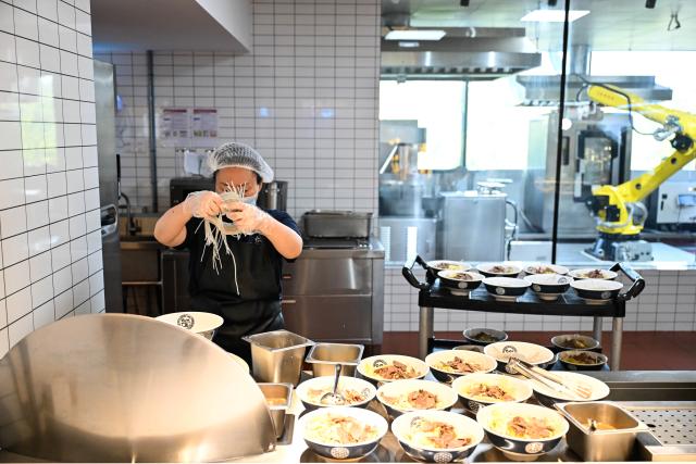 (261026) -- NANJING, Oct. 26, 2026 (Xinhua) -- A staff member works at the AI Mirror World Restaurant in Nanjing, east China's Jiangsu Province, Oct. 26, 2026. With a human-machine collaborative operation model, the restaurant makes some of its meals and drinks through standardized production powered by AI kitchen equipped with smart noodle and beverage making machines. (Xinhua/Ji Chunpeng)