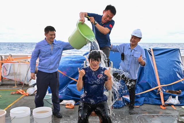 (261027) -- ABOARD RESEARCH VESSEL DEEP SEA NO. 1, Oct. 27, 2026 (Xinhua) -- Submersible pilot Zhang Yi (front) celebrates with a water splash after the manned submersible Jiaolong completed its 464th dive operation on Sept. 30, 2026. The dive reached a depth of 7,035.3 meters. China's manned submersible Jiaolong recently completed multiple 7,000-meter dive tests and returned safely, reaching a maximum depth of 7,056.9 meters. (Xinhua/Ye Haoming)