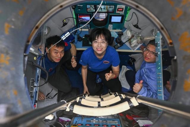 (261027) -- ABOARD RESEARCH VESSEL DEEP SEA NO. 1, Oct. 27, 2026 (Xinhua) -- Submersible pilots Tang Jialing (L), Zhang Yi (C) and maintenance worker Cheng Fei pose for a photo inside the manned submersible Jiaolong before the 464th dive on Sept. 30, 2026. China's manned submersible Jiaolong recently completed multiple 7,000-meter dive tests and returned safely, reaching a maximum depth of 7,056.9 meters. (Xinhua/Li Xin)