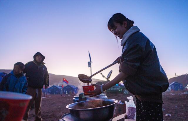 (261027) -- BAQEN, Oct. 27, 2026 (Xinhua) -- Zhe Jiaxin serves stir-fried rice noodles at a temporary shelter in Maru Township of Baqen County, Nagqu City, southwest China's Xizang Autonomous Region, Oct. 26, 2026.
  In the wake of the earthquake that struck Baqen County on Oct. 22, several volunteers rushed to the quake-affected zone to serve hot meals, sending warmth to those affected who are facing high-altitude cold in late October.
   Among them was Alimjan Haliq, a volunteer from northwest China's Xinjiang. Knowing how difficult it is to cook at high altitude, he brought two pressure cookers with him all the way to the quake zone. Zhe Jiaxin, a young woman from Xinjiang, spent nearly 48 hours on a bumpy journey through multiple cities before finally reaching the epicenter. Abdu, who runs a Xinjiang restaurant in Lhasa, quickly rallied his friends, gathered supplies, and rushed to the disaster area. Their paths were different, but they converged on the snow-covered plateau for the same purpose.
   "There is strength in numbers," Alimjan Haliq said, voicing the thoughts of every volunteer. Upon arriving in the quake zone, the rows of tidy tents and prefab houses, ample supplies, and locals helping one another deeply moved the volunteers. Zhe Jiaxin said with emotion, "I want to do all I can to help the children here feel more comfortable."
   The unceasing cook fires and hot food from the volunteers did more than fill empty stomachs -- they let the affected people feel be cared and supported. (Xinhua/Tenzin Nyida)