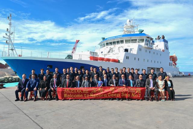(261027) -- YAREN, Oct. 27, 2026 (Xinhua) -- Naoero President David Adeang and other officials pose for a group photo with Chinese researchers in front of China's research vessel Deep Sea No. 1 berthed at Aiwo Port in Naoero, Oct. 26, 2026.
  China's research vessel Deep Sea No. 1, carrying manned deep-sea submersible Jiaolong, on Monday visited Naoero and held an ocean-themed open day event here. (Xinhua/Li Xin)
