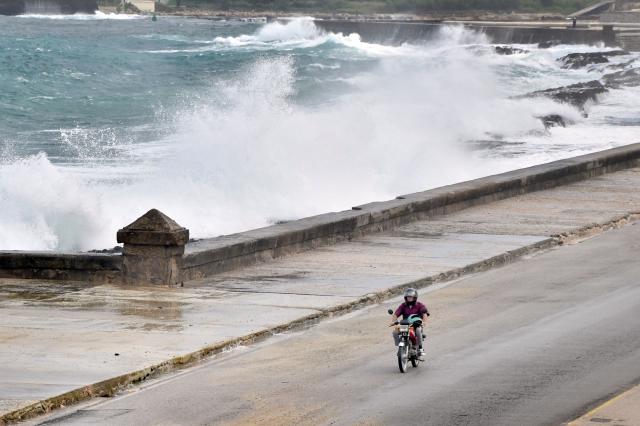 (261027) -- HAVANA, Oct. 27, 2026 (Xinhua) -- A motor motorcyclist rides along the Malecon Avenue as waves crash against the seashore in Havana, Cuba, Oct. 27, 2026. (Photo by Joaquin Hernandez/Xinhua)