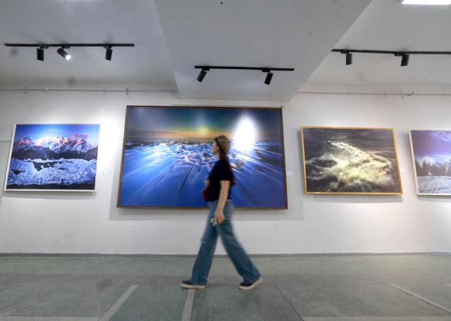 (261028) -- BISHKEK, Oct. 28, 2026 (Xinhua) -- A woman walks past exhibits displayed at an art and photography exhibition showcasing the magnificent landscapes and diverse culture of northwest China's Xinjiang Uygur Autonomous Region in Bishkek, Kyrgyzstan, Oct. 27, 2026. The two-week exhibition opened at the Kyrgyz National Museum of Fine Arts on Tuesday, featuring 40 selected artworks and photographs about Xinjiang. (Photo by Roman/Xinhua)