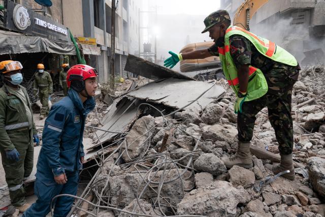 (261028) -- NAIROBI, Oct. 28, 2026 (Xinhua) -- A Chinese rescuer (2nd R) communicates with a local rescuer at the site of a building collapse in Eastleigh, Nairobi, Kenya, on Oct. 27, 2026. TO GO WITH "Chinese rescue team detects signs of life beneath collapsed building in Kenya's Nairobi" (Xinhua/Xie Jianfei)