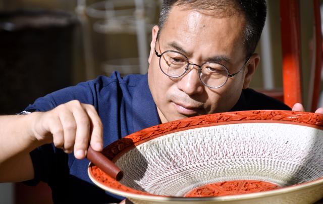 (261028) -- BEIJING, Oct. 28, 2026 (Xinhua) -- Zhu Jiang polishes a piece of work of the carved lacquer craft on porcelain body in Beijing, capital of China, Oct. 26, 2026.
  Born in 1976, Zhu Jiang, a master of arts and crafts of Beijing, is an inheritor of the carved lacquer art.
  The carved lacquer craft on porcelain body is a unique art form that combines two traditional Chinese crafts, porcelain and carved lacquer ware making, into a single piece.
  Through years of studying and practicing, Zhu has overcome a series of difficulties to achieve a better presentation of this craft. (Xinhua/Li Xin)