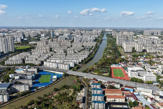 (261028) -- RUDONG, Oct. 28, 2026 (Xinhua) -- An aerial drone photo taken on Oct. 27, 2026 shows students exercising on a playground near the Jueju River in Rudong County of Nantong City, east China's Jiangsu Province. In recent years, Rudong County in Nantong City has made efforts to improve its aquatic ecological environment. Water environment of the three rivers, namely the Taiyun River, the Jueju River and the Juekan River, which run through the county, has undergone sound remediation. Along these waterways, the Heming Park and the bank areas of tributaries have all formed a picturesque urban landscape for people to enjoy their leisure time. (Xinhua/Ji Chunpeng)